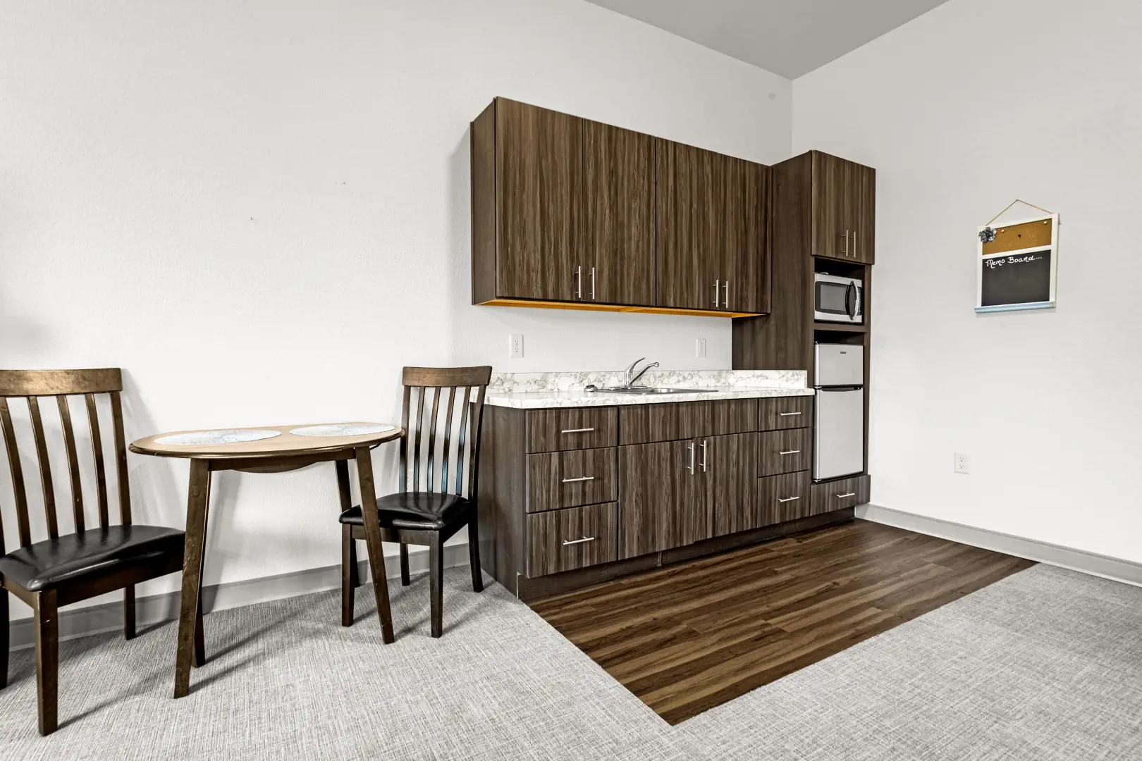 Kitchenette in studio apartment at Greeley Village has a sink, cabinets, small refrigerator and microwave.